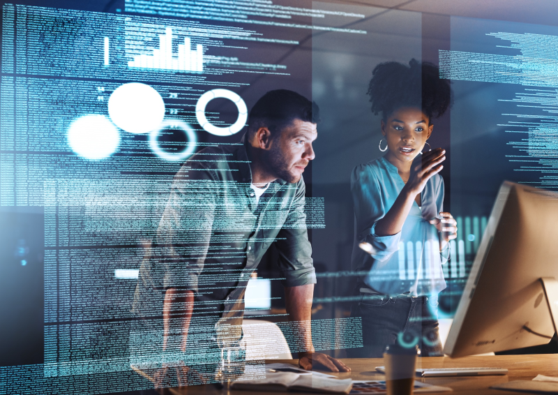 Two people, code displayed on computer, working together.