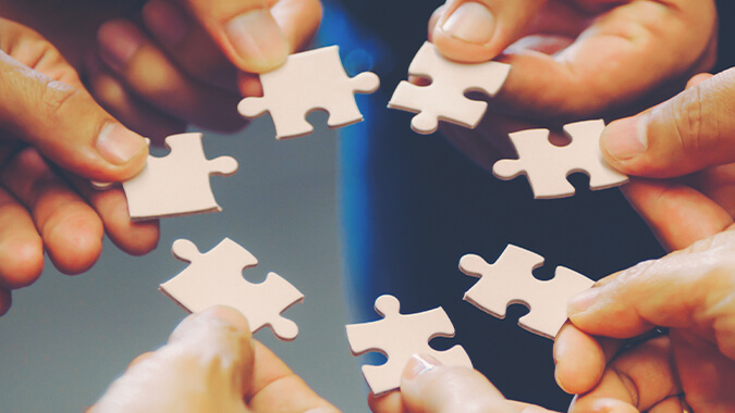Hands holding puzzle pieces, representing collaboration and problem-solving.