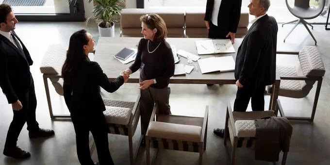 Business people shaking hands in meeting room, agreement.