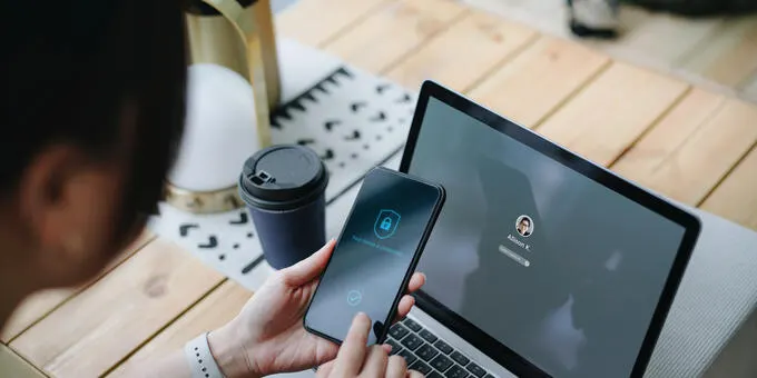 Smartphone and laptop with security screen, cup and coffee.
