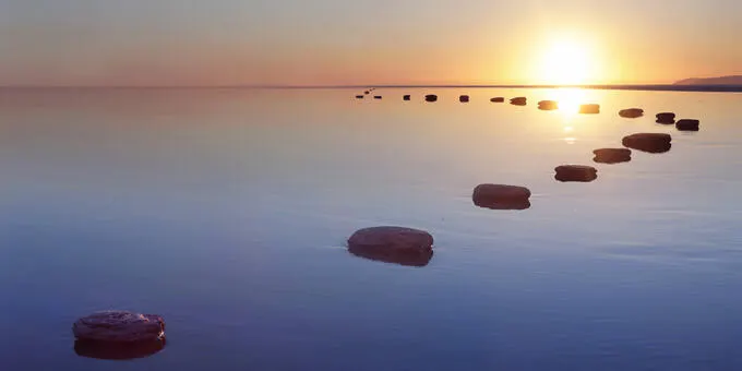 Stones across water at sunset.