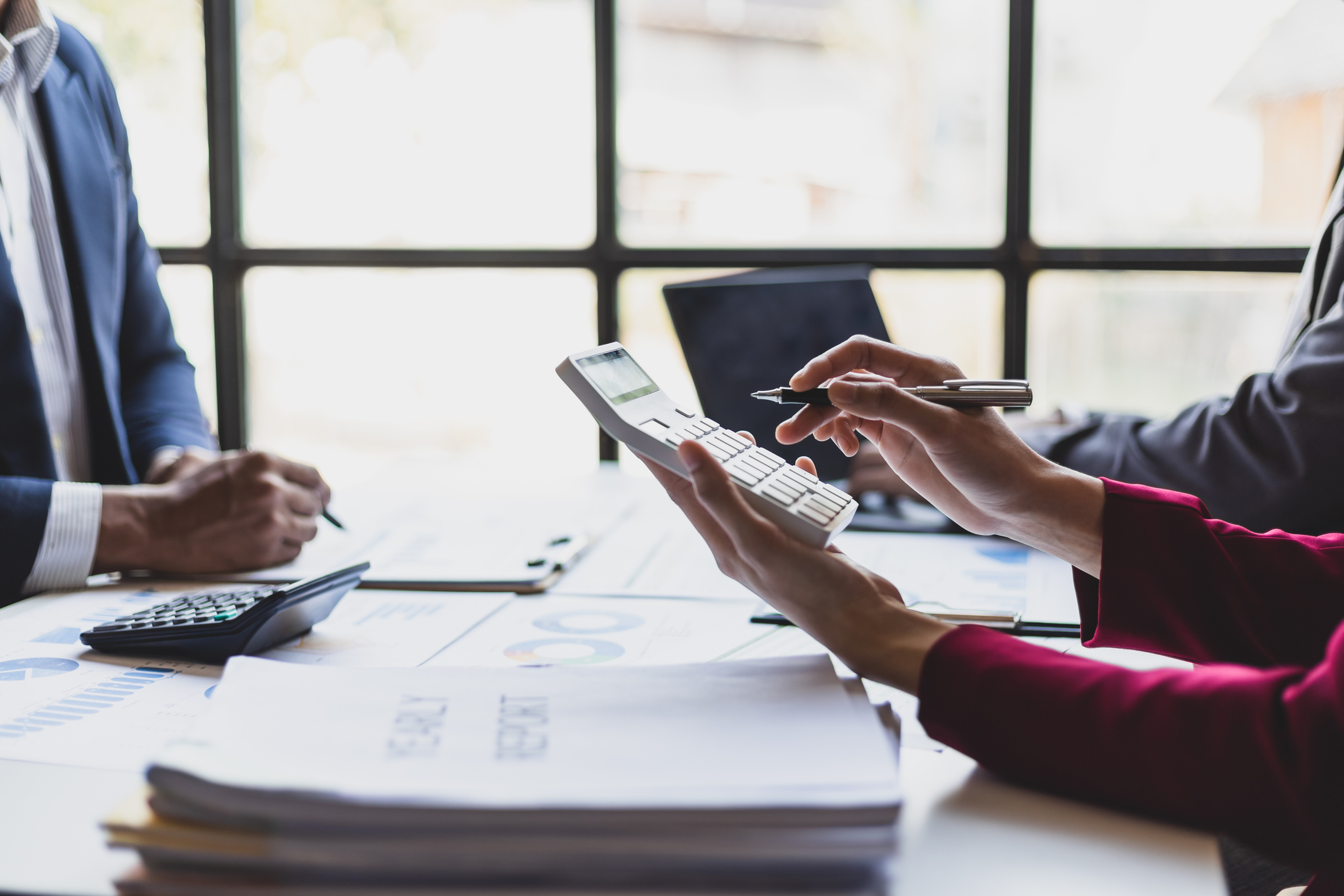 People working on a financial report with calculator and documents.