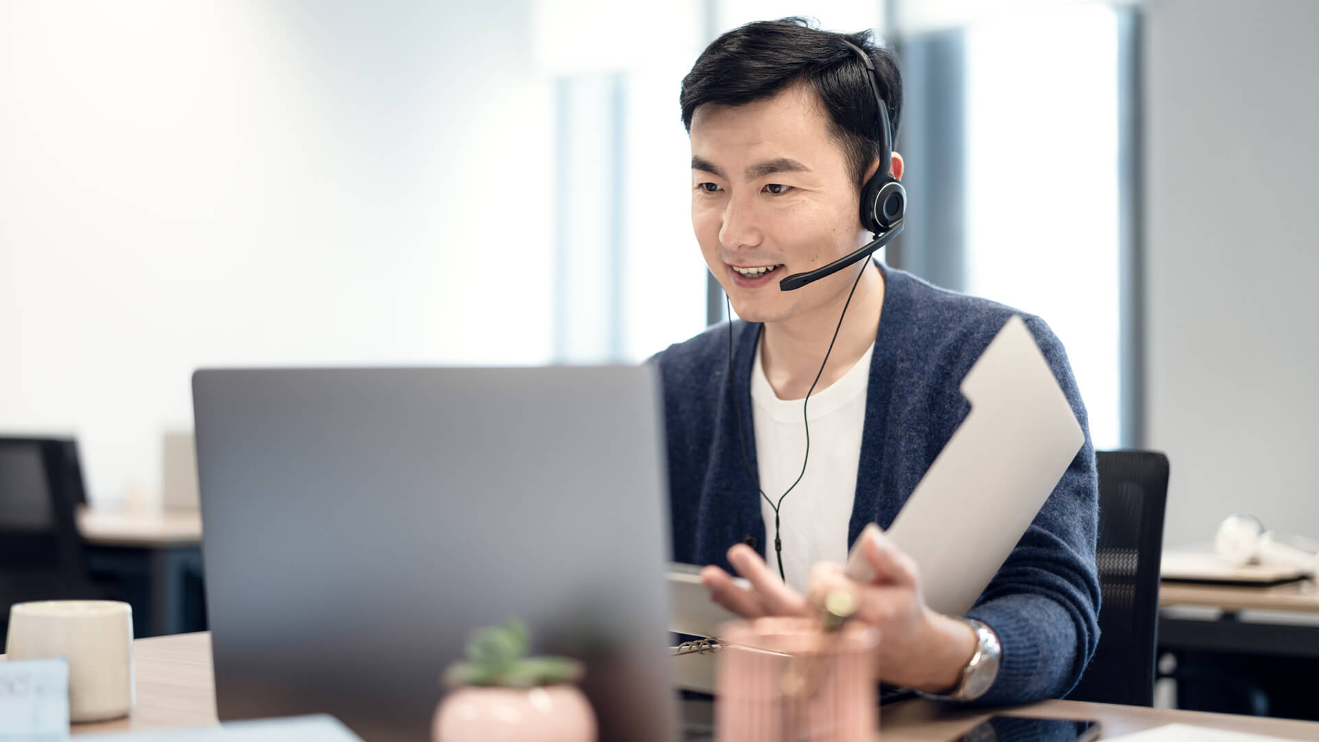 Man with headset in front of a laptop and documents.