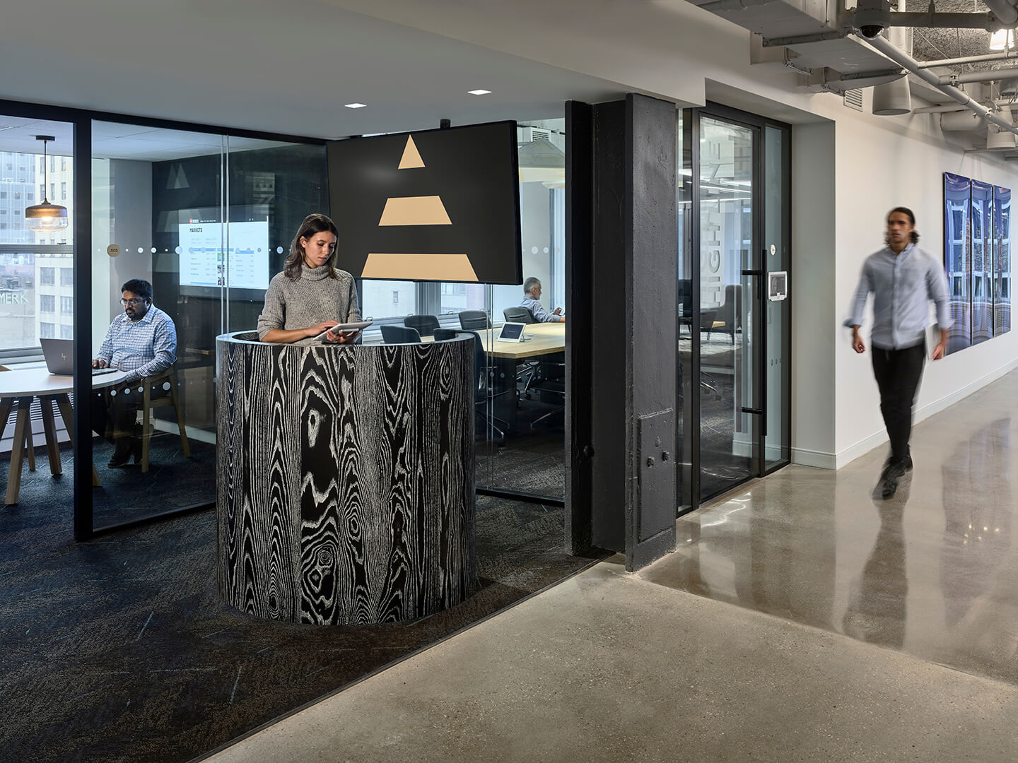Woman at reception desk, other workers in background.