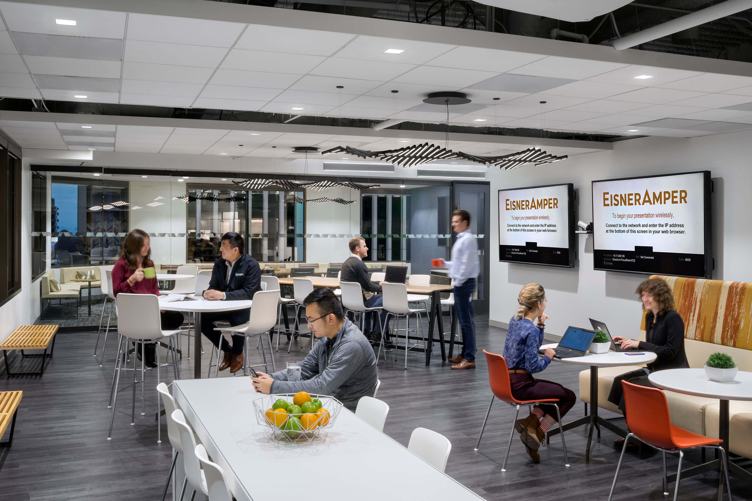 People working, using laptops, and socializing in an office common area.