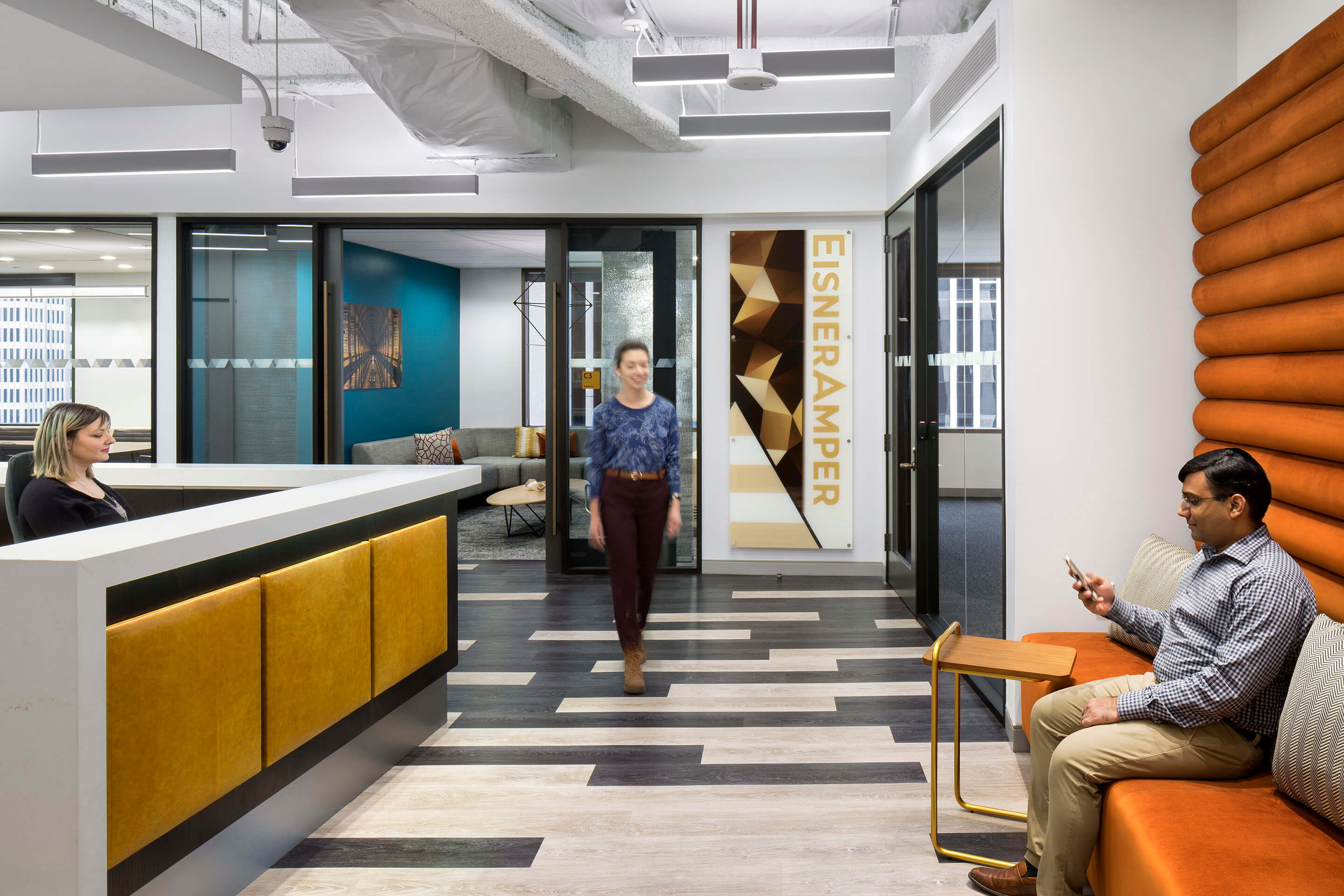 Office interior with employees, modern design, and EisnerAmper logo.