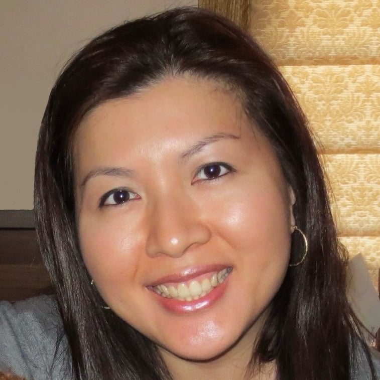 Smiling woman with dark hair and hoop earrings.