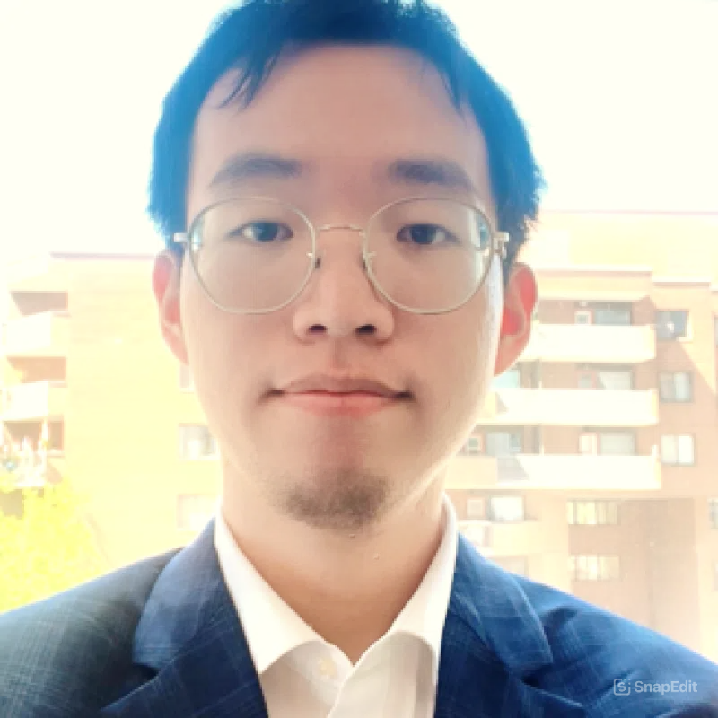 A man wearing glasses and a suit in front of a building.