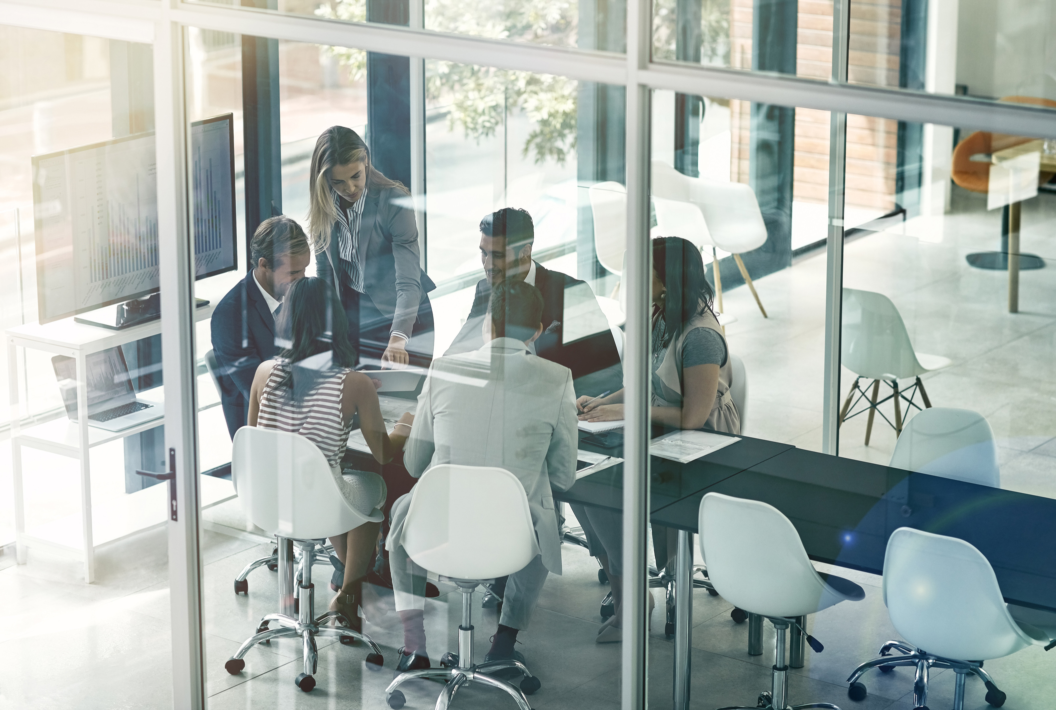 Group of people in meeting around table. Reflections on glass.
